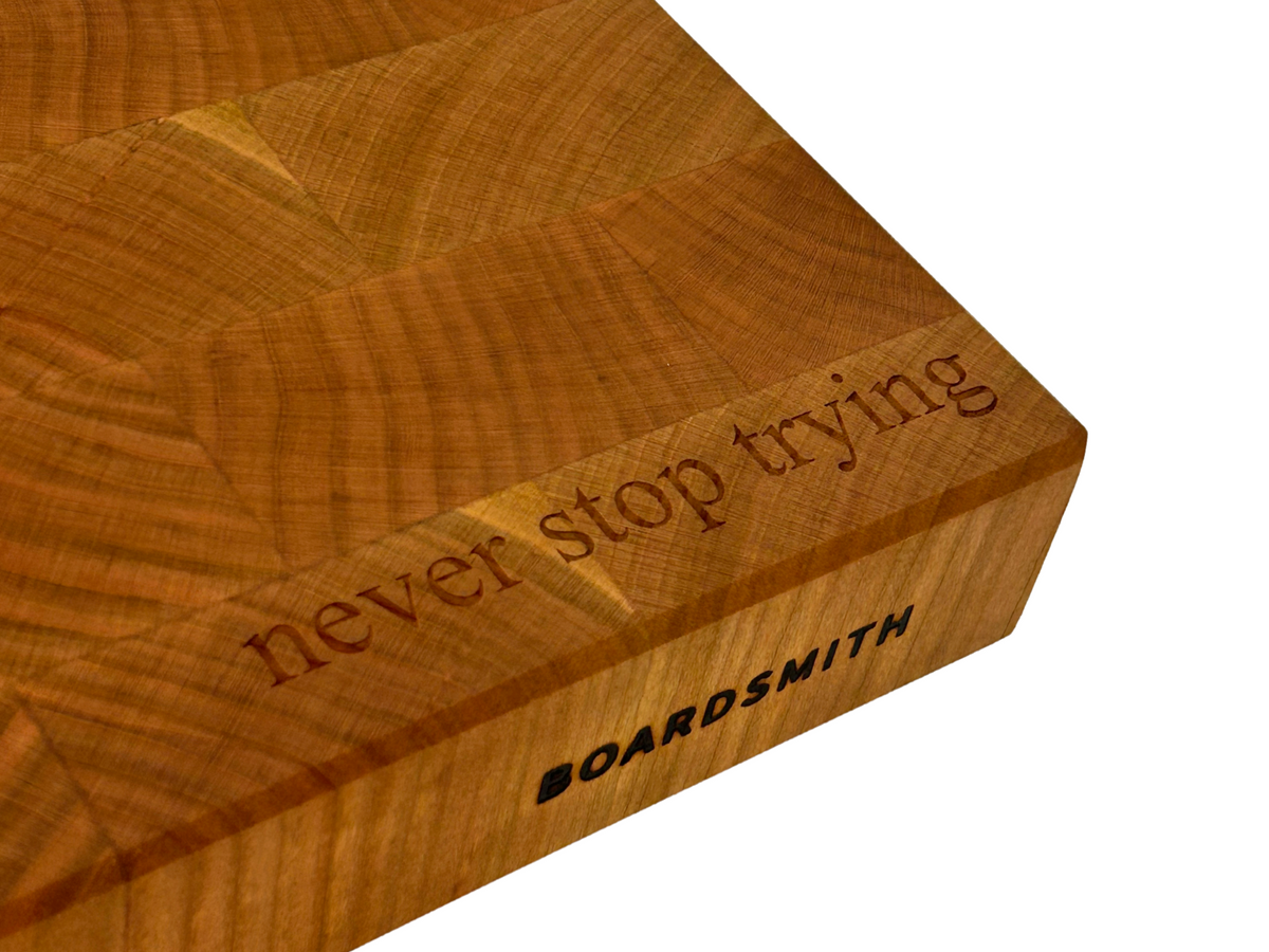 Cherry cutting board engraved with the phrase never stop trying and Boardsmith logo